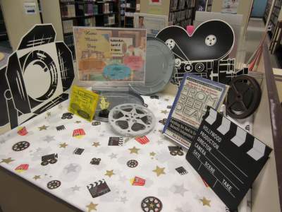 Home Movie Day Welcome Table with cutouts of a clapper, studio light fixture, and film camera.