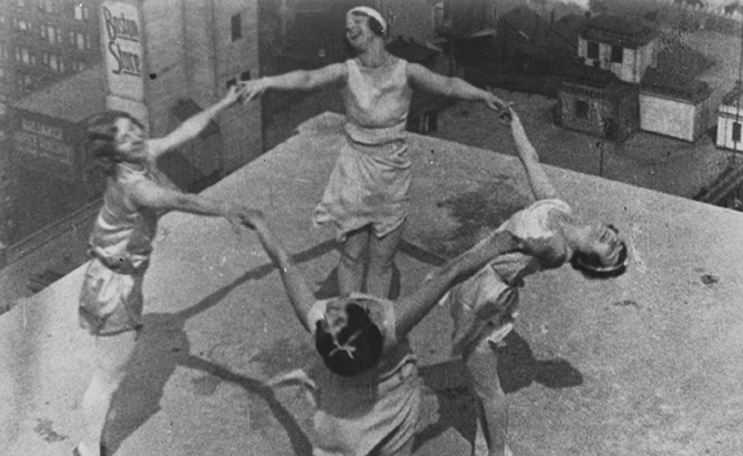 A still from The Inheritance (1964) depicting four women on top of a building holding hands to form a ring.