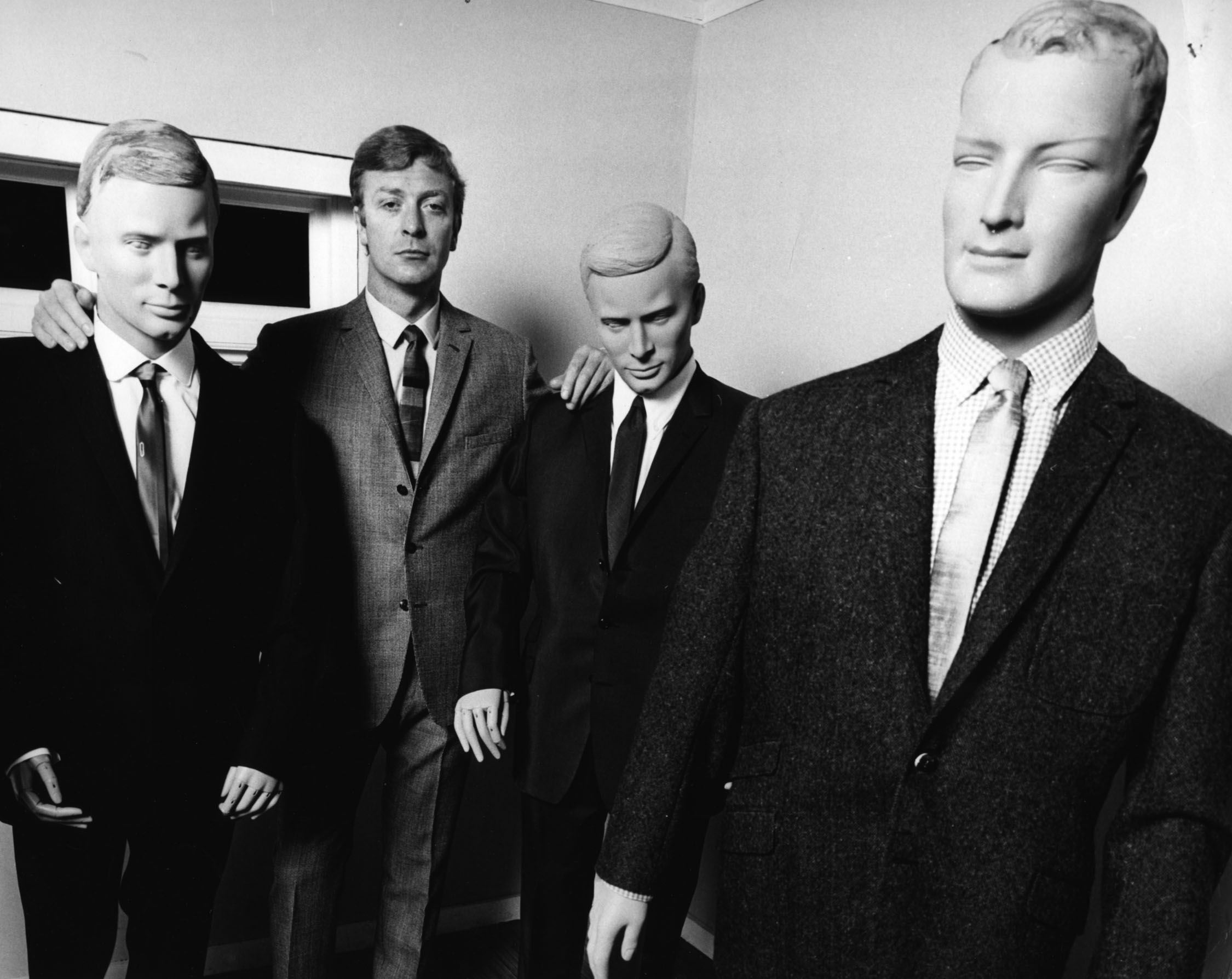 Michael Caine, star of Alfie (1966), poses with suits made to promote the film.