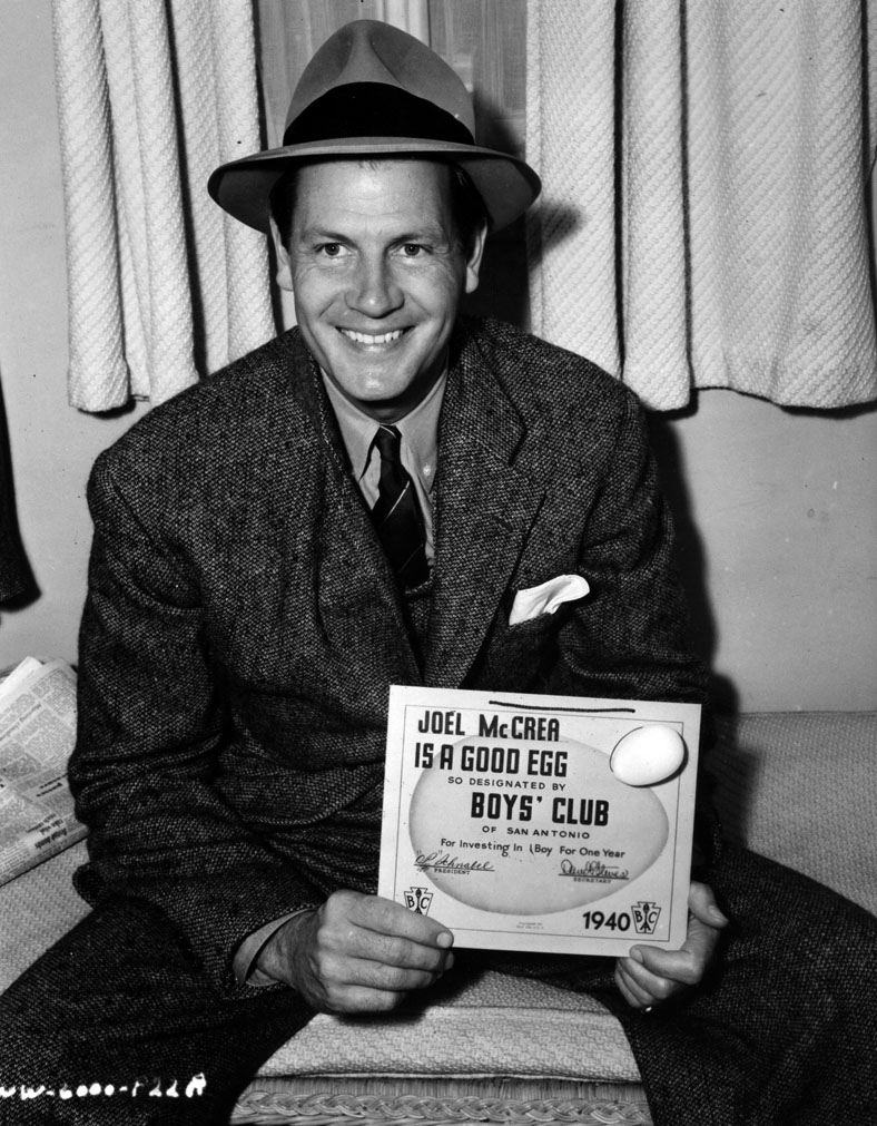 Joel McCrea poses with a "Good Egg" certificate from the Boy's Club of San Antonio