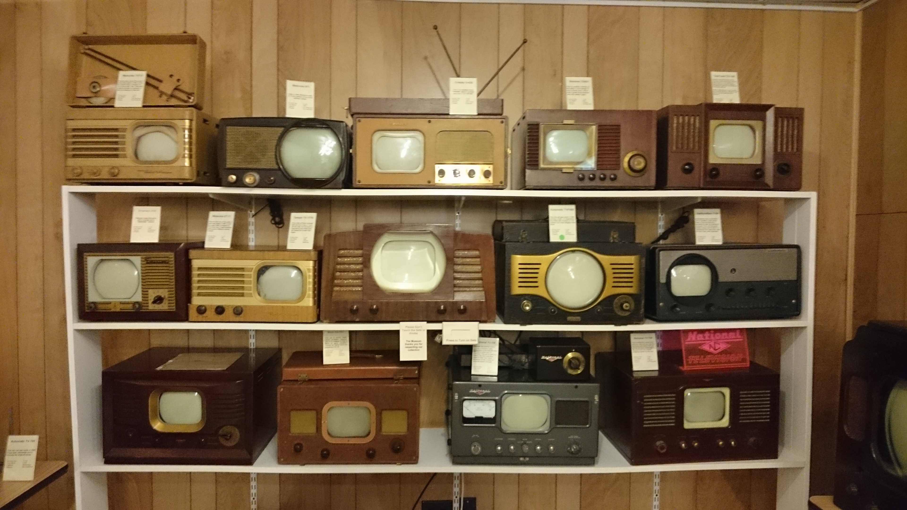 Several small wooden television sets on a shelf.